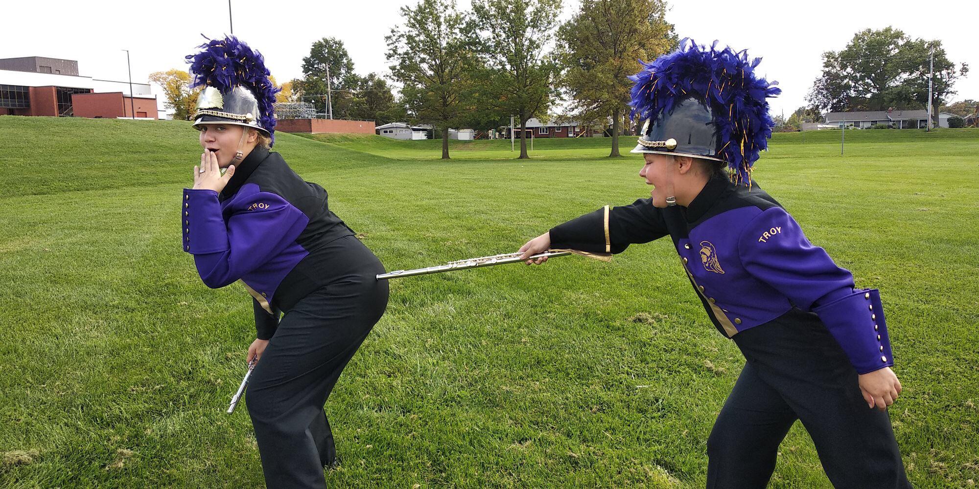 a flute player poking another flute player in the butt with their flute